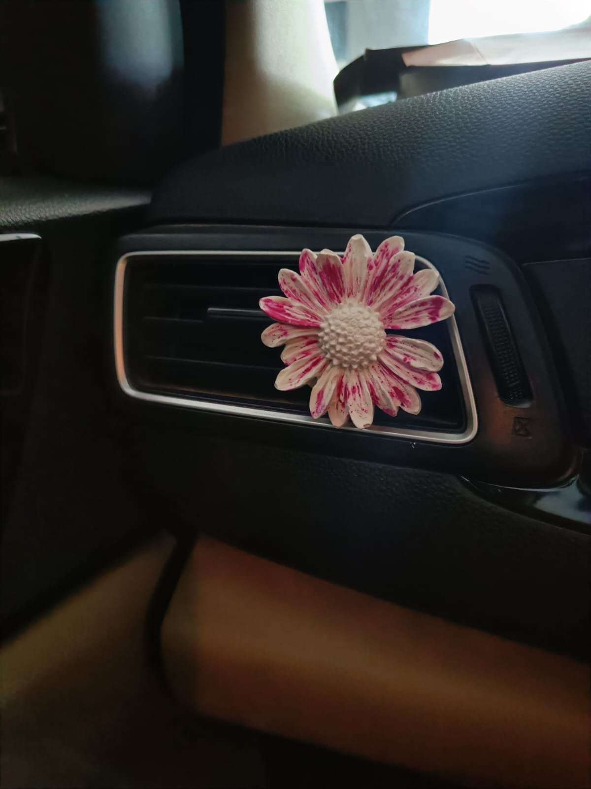 Pink and white daisy car vent aroma stone clipped to an air vent